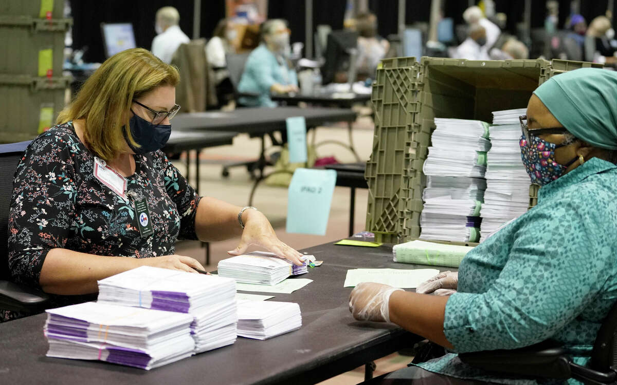 Members of the signature verification committee work on processing mail in ballots at NRG Arena Wednesday, Oct. 21, 2020 in Houston.