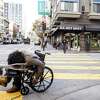 2022年12月15日，星期四，在加利福尼亚州旧金山田德隆社区的特克和泰勒街拐角处，一个人坐在轮椅上休息。