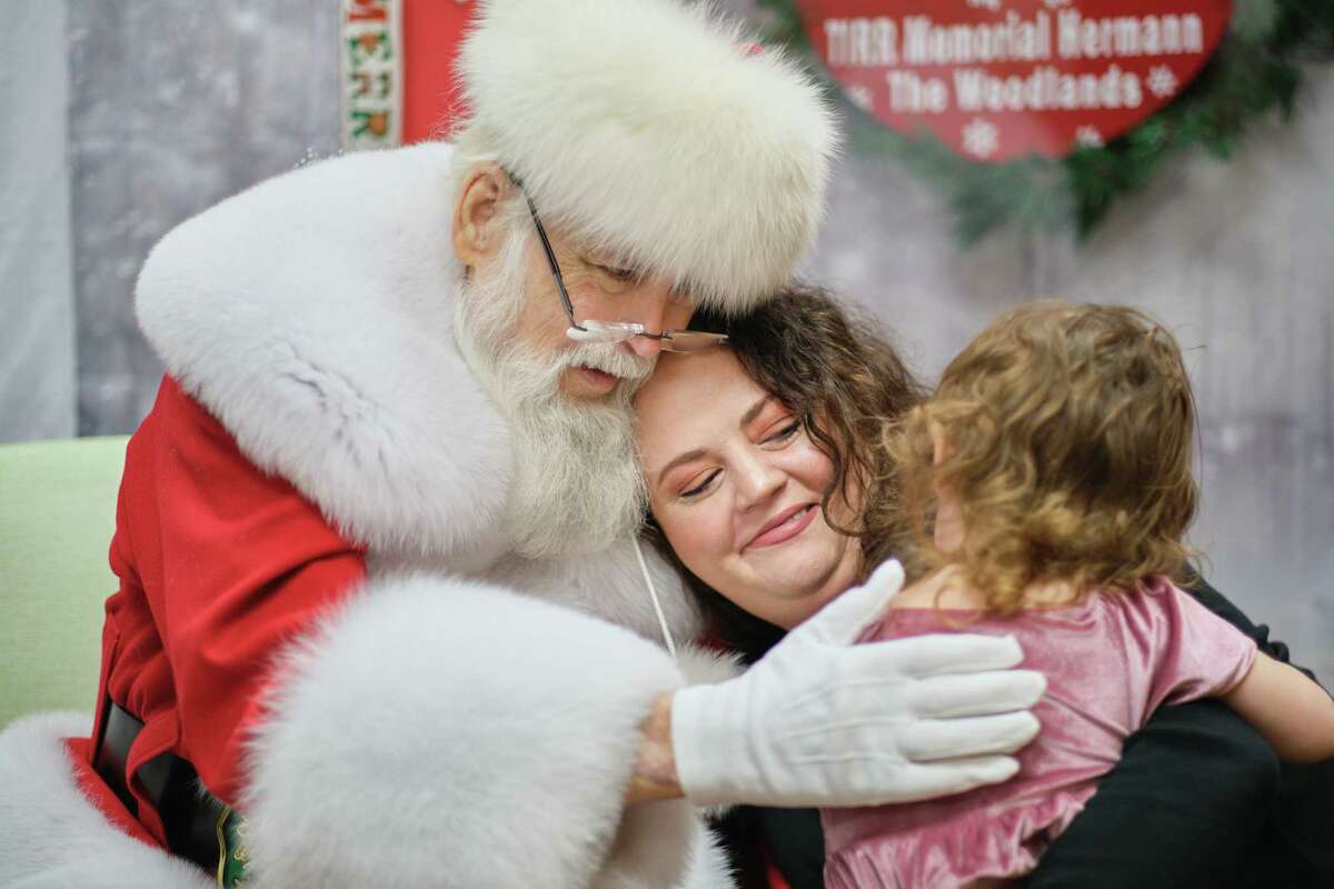 in {The Woodlands}, {Thursday}, {December} {15}, {2022.} During their visit to see Santa at TIRR Memorial Hermann in The Woodlands, Maddy Hall (C) and Vivienne Lee (R) give Santa, Deryl McKenzie (R) a hug. December 15, 2022