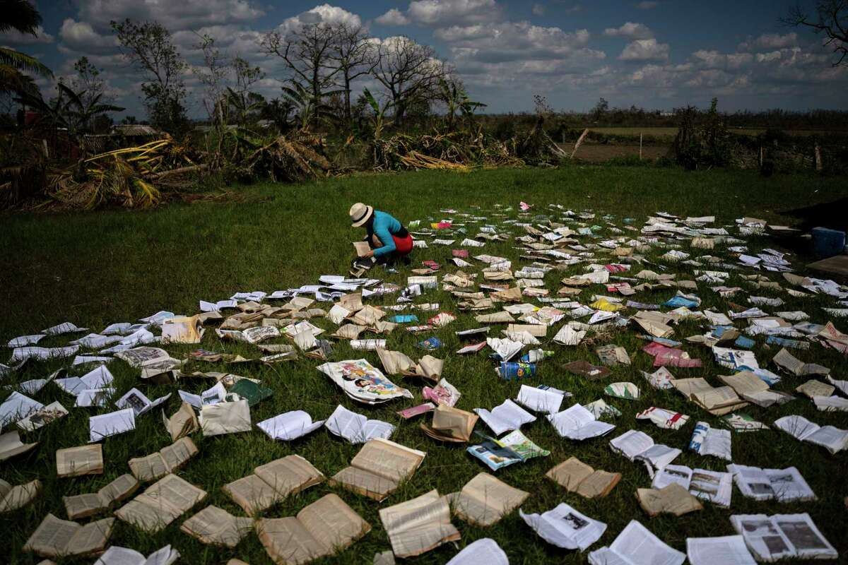 A teacher dries out books at a school that was heavily damaged by Hurricane Ian in La Coloma, in the province of Pinar del Rio, Cuba, on Oct. 5, 2022.