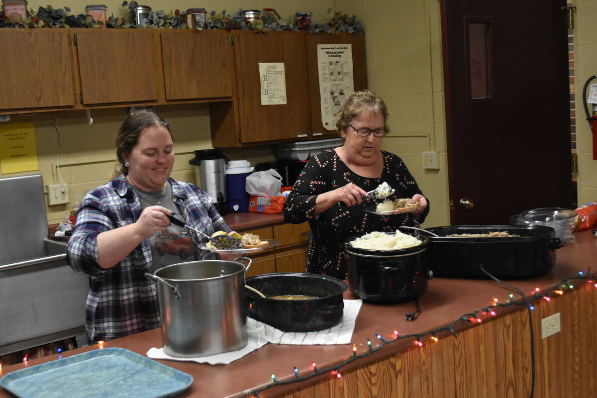 Elaine Sanford (right) and her daughter serve their Christmas dinner of meat, potatoes and vegetables. Sanford hosted her annual free Christmas dinner for some of the area elderly at the Parkview Highrise dinning area on Thursday.