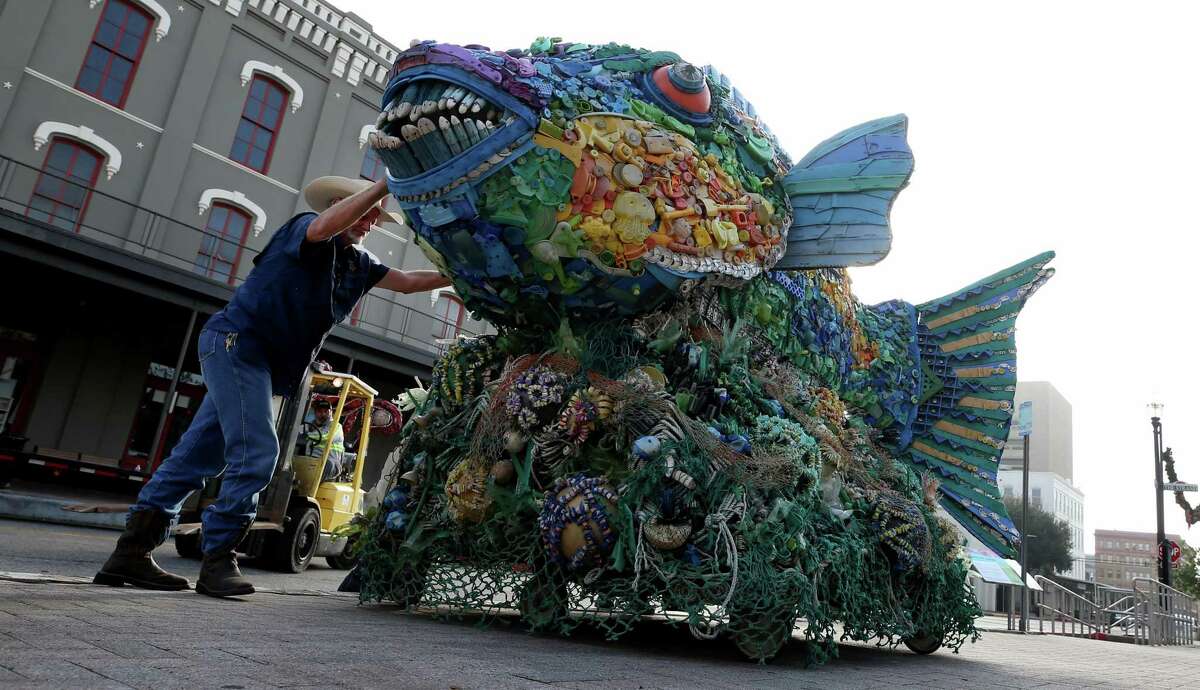 Larry Jackson, with the Galveston Island Park Board, maneuvers the “Priscilla the Parrot Fish” sculpture onto the sidewalk at Saengerfest Park in Galveston on Friday, Dec. 9, 2022. The large sculpture, made from plastic debris from the beaches in Oregon, is one of 20 being displayed around the island through March 5.