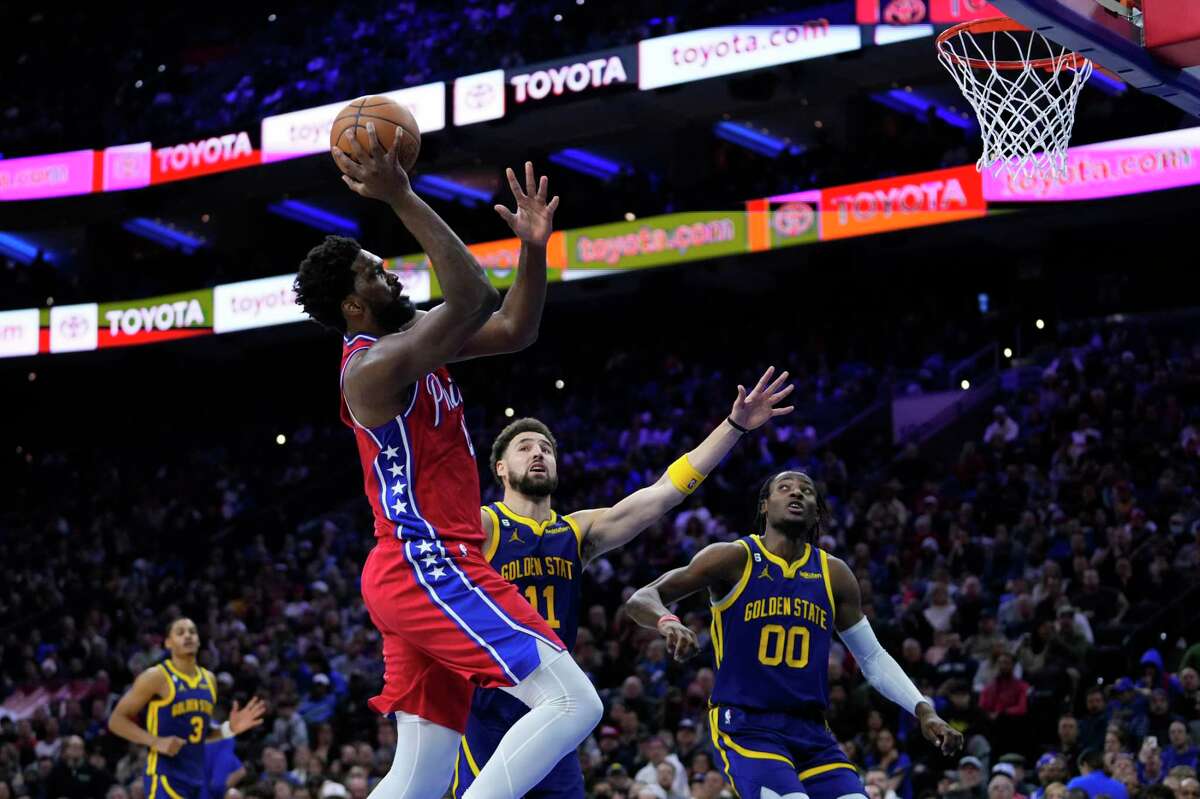 Philadelphia’s Joel Embiid goes up for a shot against Golden State’s Klay Thompson (center) and Jonathan Kuminga during the second half of Friday’s game in Philadelphia.
