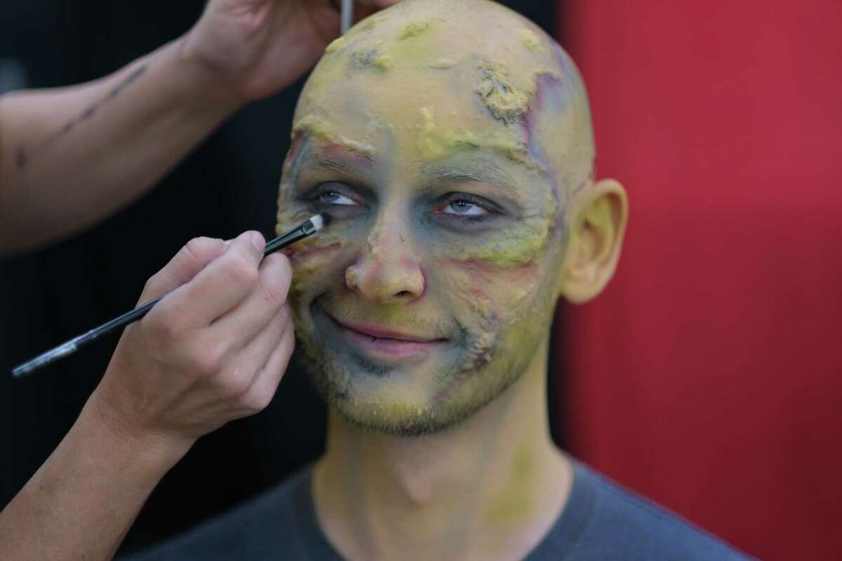 Chris McAuliffe smiles while getting special effects to resemble a zombie during TerrorFest on Saturday in Conroe