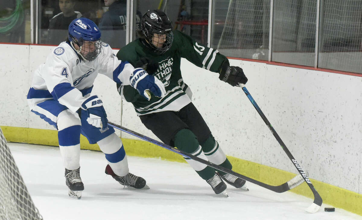 Darien's Tommy Holland (4) and Northwest Catholic's Jack Breen (19) battle for the puck during a boys ice hockey game at the Darien Ice House on Saturday, Dec. 17, 2022.