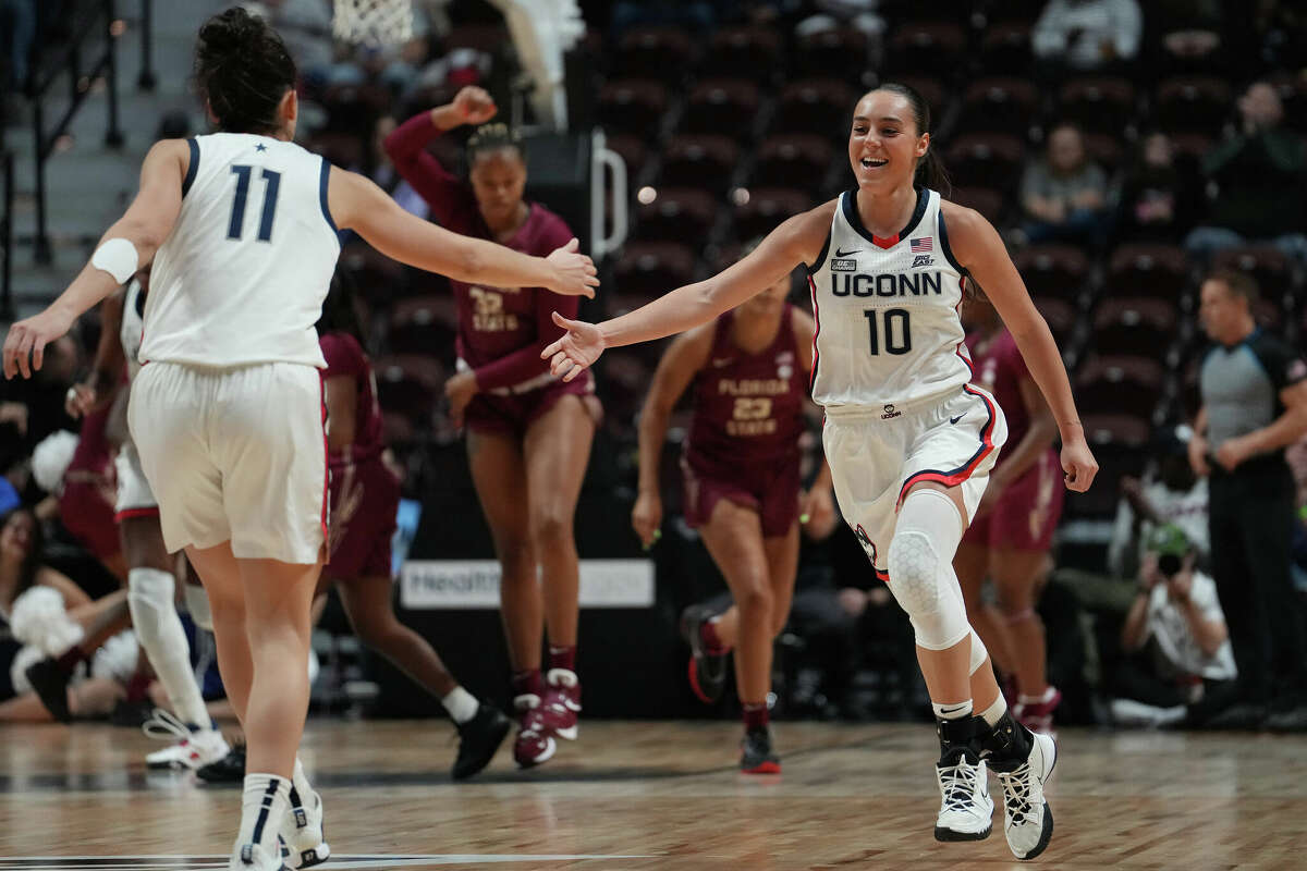 : Lou Lopez Senechal #11 and Nika Muhl #10 of the UConn Huskies celebrate against the Florida State Seminoles during the first half of an Invesco QQQ Basketball Hall of Fame Women's Showcase game at Mohegan Sun Arena on December 18, 2022 in Uncasville.