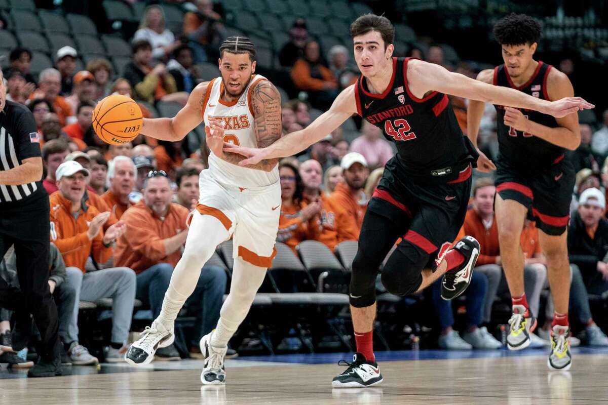 Texas forward Timmy Allen (0) drives past Stanford forward Maxime Raynaud (42) on a fast break during the first half of an NCAA college basketball game, Sunday, Dec. 18, 2022, in Dallas. (AP Photo/Jeffrey McWhorter)