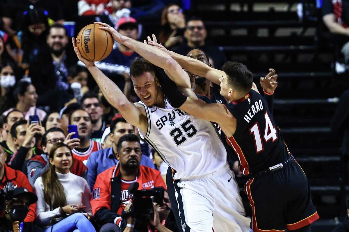 The Spurs’ Jakob Poeltl struggles for the ball against Tyler Herro of the Miami Heat during Saturday’s game in Mexico City.