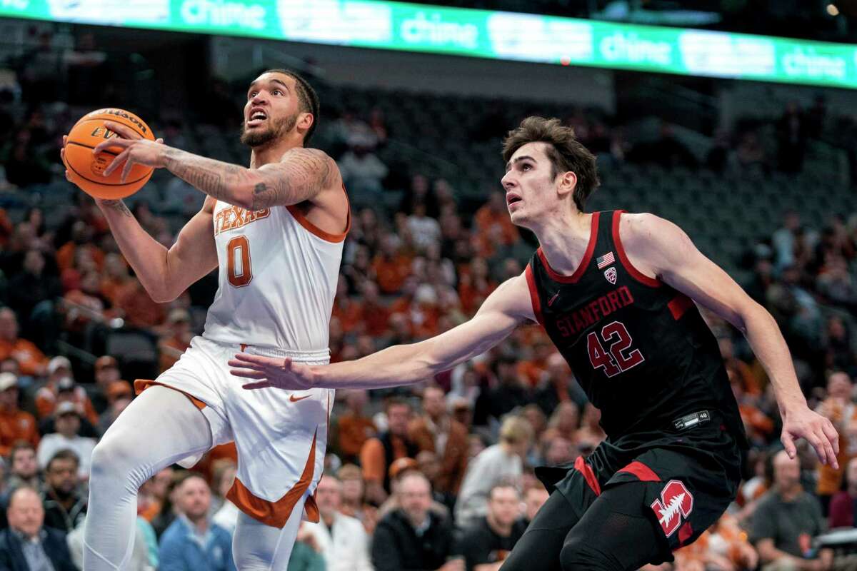Texas forward Timmy Allen (0) goes up for a layup against Stanford forward Maxime Raynaud (42) during the first half of an NCAA college basketball game Sunday, Dec. 18, 2022, in Dallas. (AP Photo/Jeffrey McWhorter)