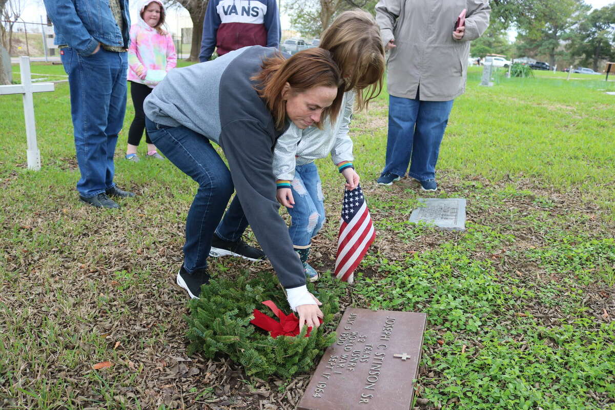 Staci Simmons, along with granddaughter Aubree Simmons, lays a wreath Saturday at the grave of World War I veteran Joseph Stinson Sr. during a Wreaths Across America event at Crown Hill Cemetery in Pasadena.