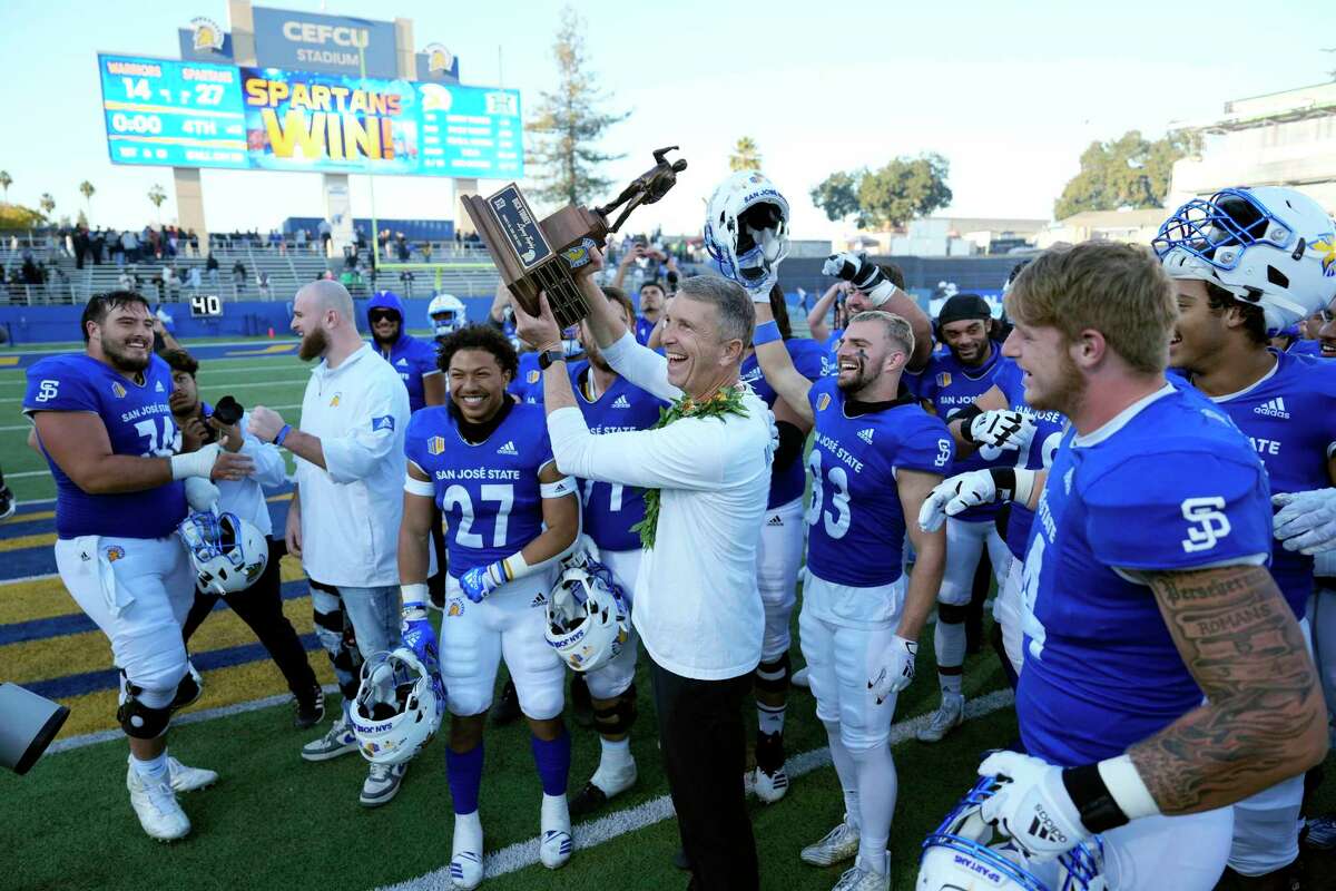 San Jose State head coach Brent Brennan, center, holds up the Dick Tomey Legacy trophy after defeating Hawaii 27-14 in an NCAA college football game, Saturday, Nov. 26, 2022, in San Jose, Calif. (AP Photo/Tony Avelar)