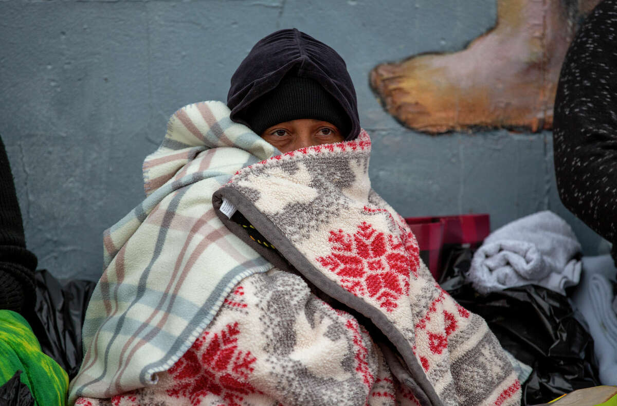 A migrant covers himself with blankets while waiting for help in downtown El Paso, Texas, Sunday, Dec. 18, 2022. Texas border cities were preparing Sunday for a surge of as many as 5,000 new migrants a day across the U.S.-Mexico border as pandemic-era immigration restrictions expire this week, setting in motion plans for providing emergency housing, food and other essentials. (AP Photo/Andres Leighton)