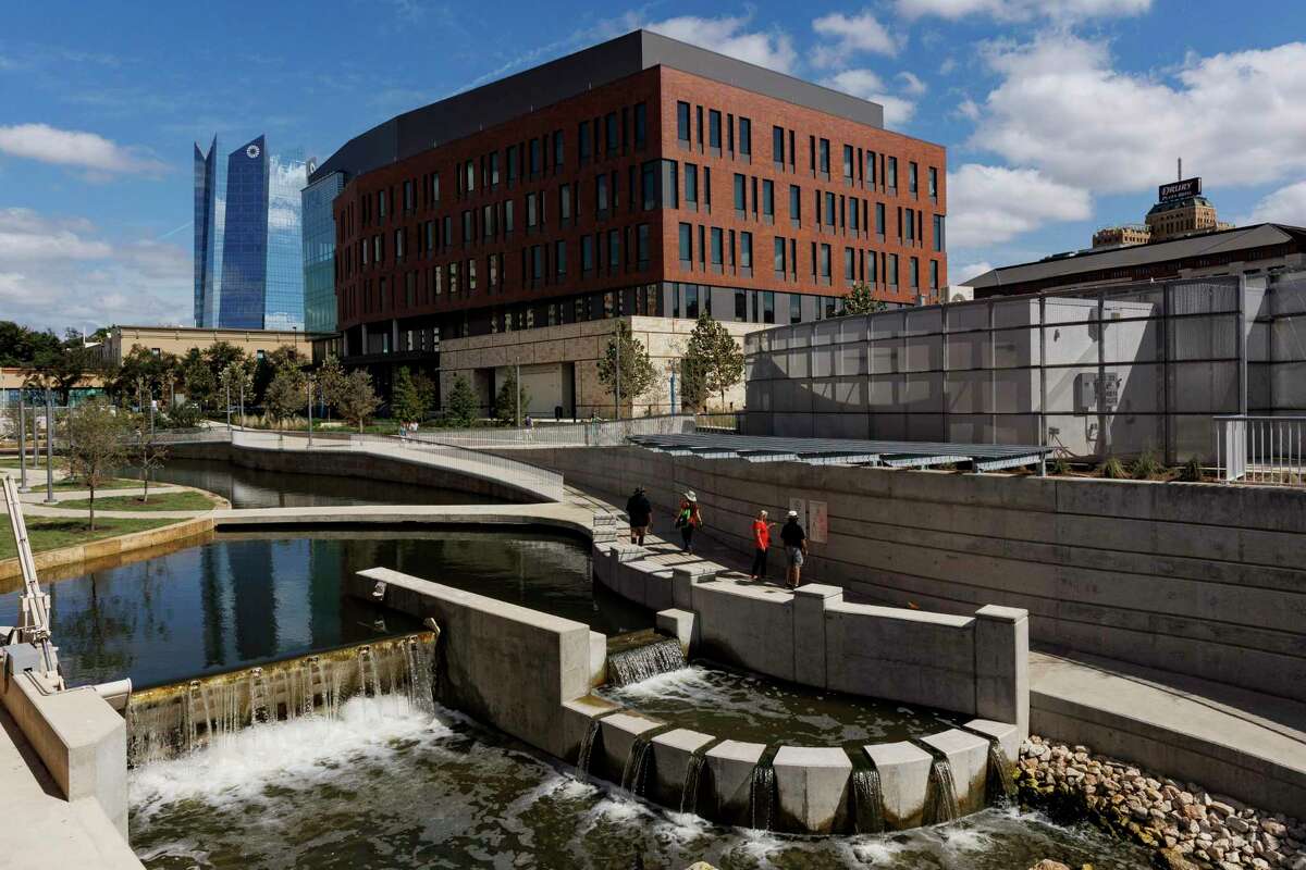 People walk along the newest section of San Pedro Creek Culture Park on a sunny day in downtown San Antonio.
