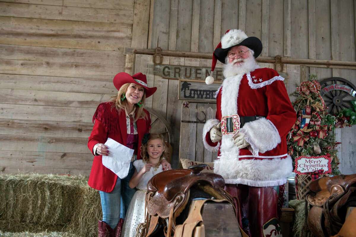 Reneé Davis — CEO of Santa Express, a Santa-for-hire business — and Gene Davis, aka Cowboy Kringle, pose for pictures with Emberlee Gonzalez, 5, during the Photos with Cowboy Kringle event in Gruene on Dec. 17.