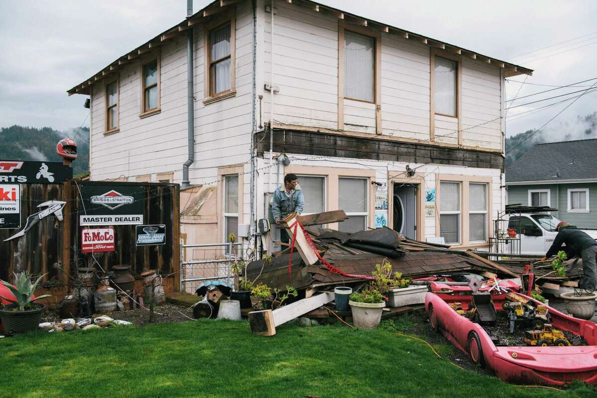 Darren Gallagher works with a neighbor on taking apart the balcony which fell off the front of his house in Rio Dell, Calif. as a result of the earthquake on Dec. 20, 2022.