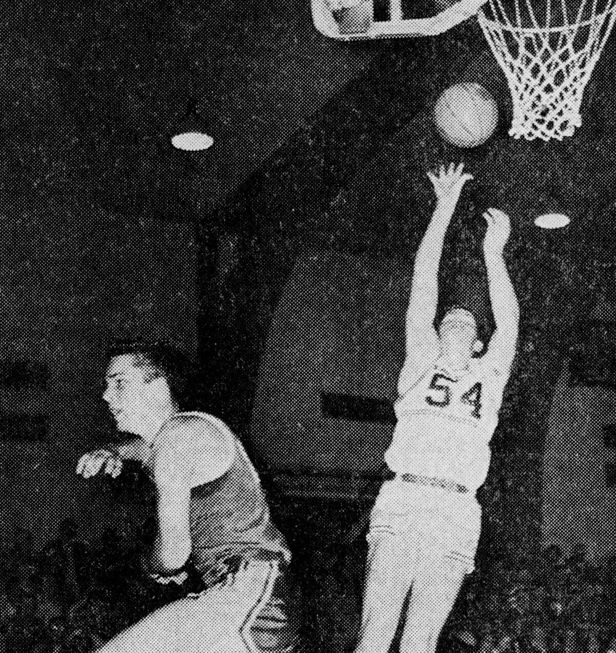 The Scottville player appears to have taking up dancing in preference to guarding Manistee's Jim Ogilvie (54) as he goes up for two points in the game at the Armory last night which saw the Chippewas win by a score of 72-60. The photo was published in the News Advocate on Dec. 22, 1962.