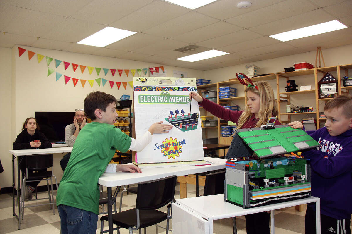 Three students from St. John Neumann Catholic School in Maryville discuss their project called Electric Avenue. Two robotics teams from the school have earned the right to compete in a statewide meet on Jan. 28 in Champaign. 