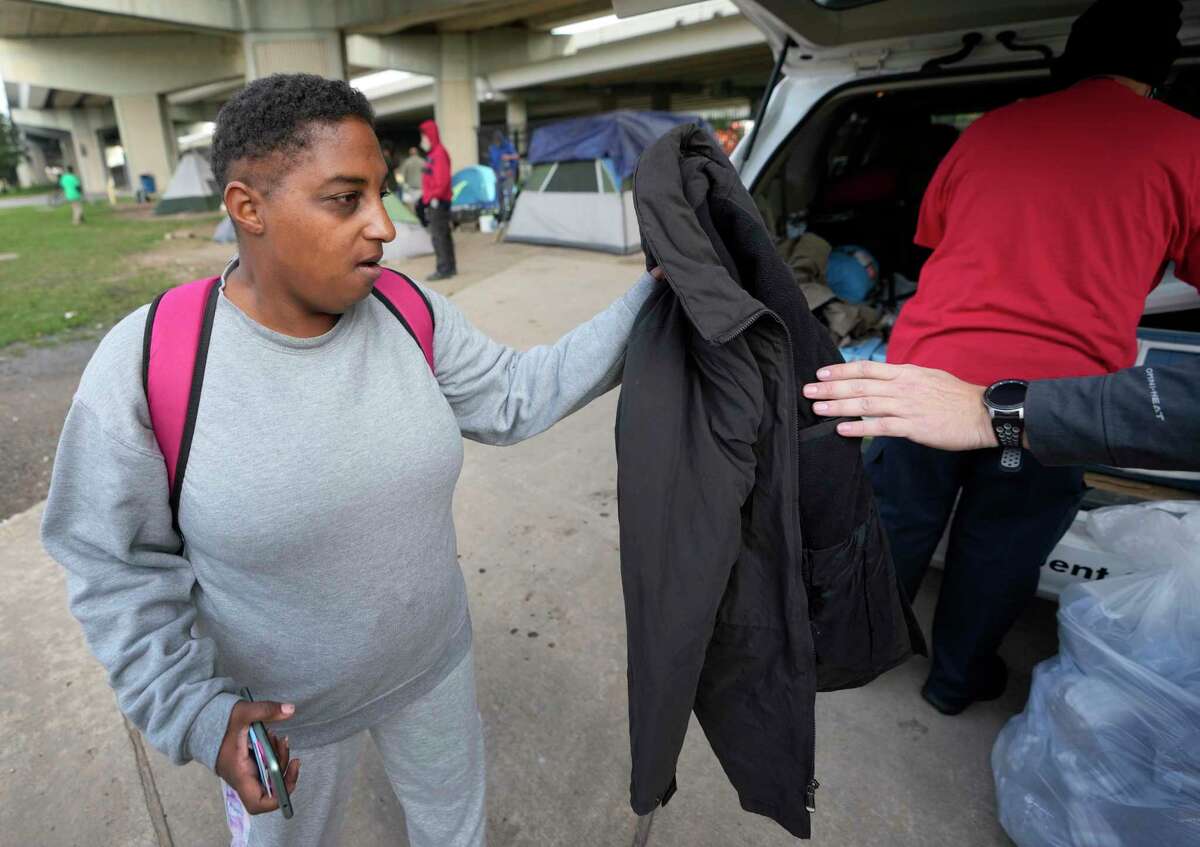 Deondria Williams receives a coat as the Star of Hope’s team members distribute blankets and coats from the “Love In Action” van ahead of the arctic cold front Wednesday, Dec. 21, 2022, in Houston. Deondria said she will be going to the George R. Brown warming center tomorrow.