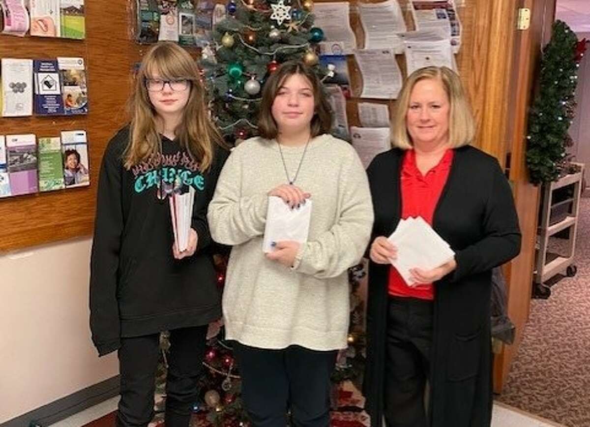 From left to right, Seventh graders Makaylynn Richards and Emberlee Pruyne, with their teacher, Nancy Reed, drop off Christmas cards for seniors who get home delivered meals from Benzie Senior Resources. 