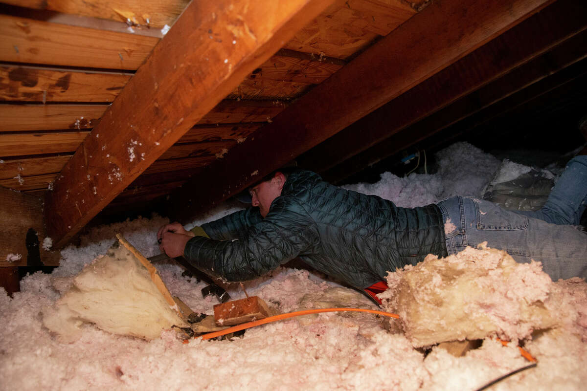 Nick Conway crawls into his attic and fixes a burst water pipe, due to the cold weather, with a repair tape Wednesday, Feb. 17, 2021, in Houston.
