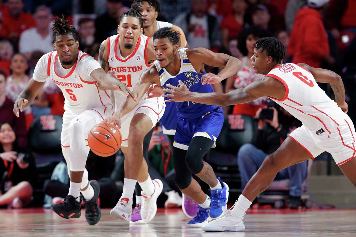 McNeese State guard Trae English, center, gets to the ball between Houston forward Ja'Vier Francis (5), guard Emanuel Sharp (21) and guard Marcus Sasser (0) during the first half of an NCAA college basketball game Wednesday, Dec. 21, 2022, in Houston. (AP Photo/Michael Wyke)