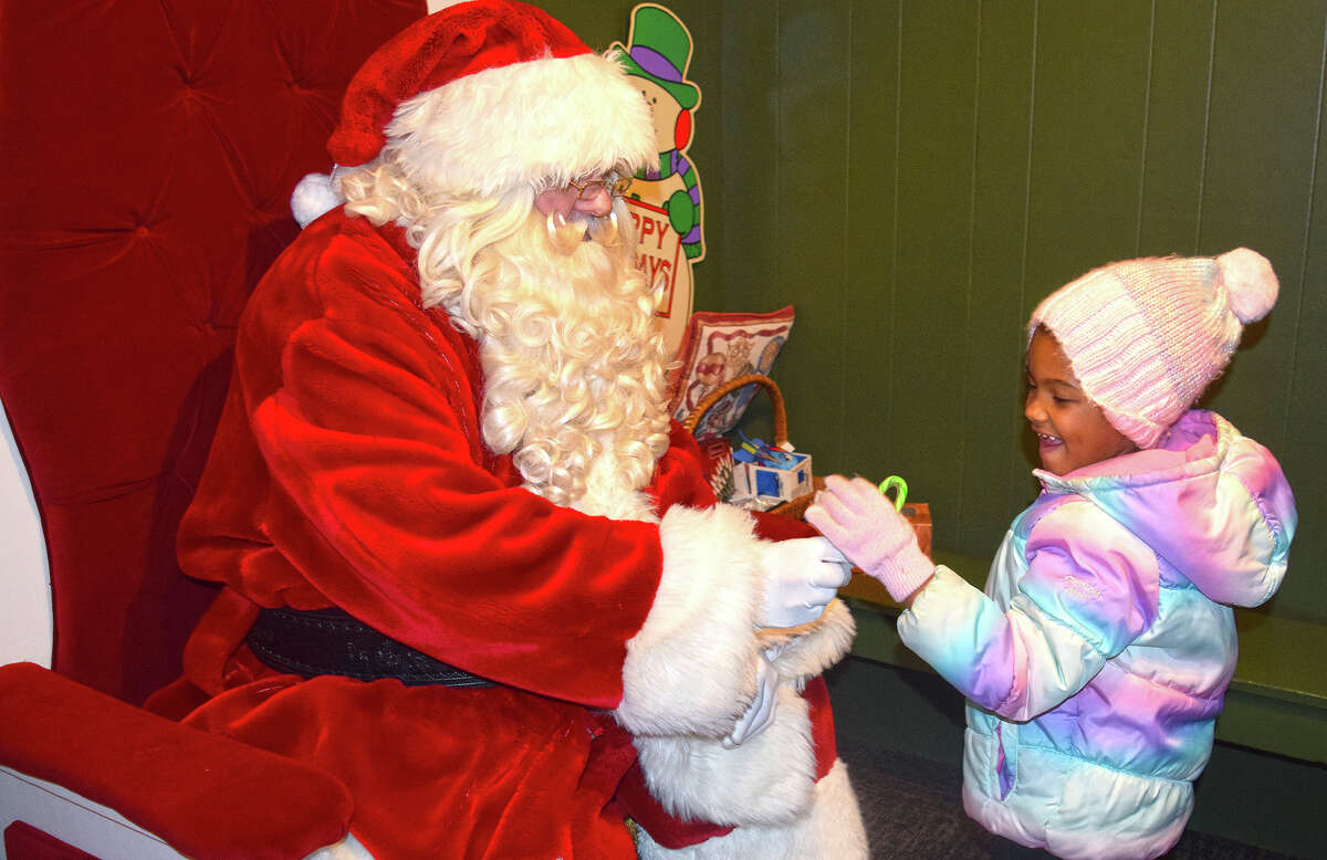 Malay Clinton, 5, daughter of Cortez Clinton and Geneva Powell, receives a candy cane Wednesday evening from Santa Claus at Santa's house on the downtown Jacksonville square. 