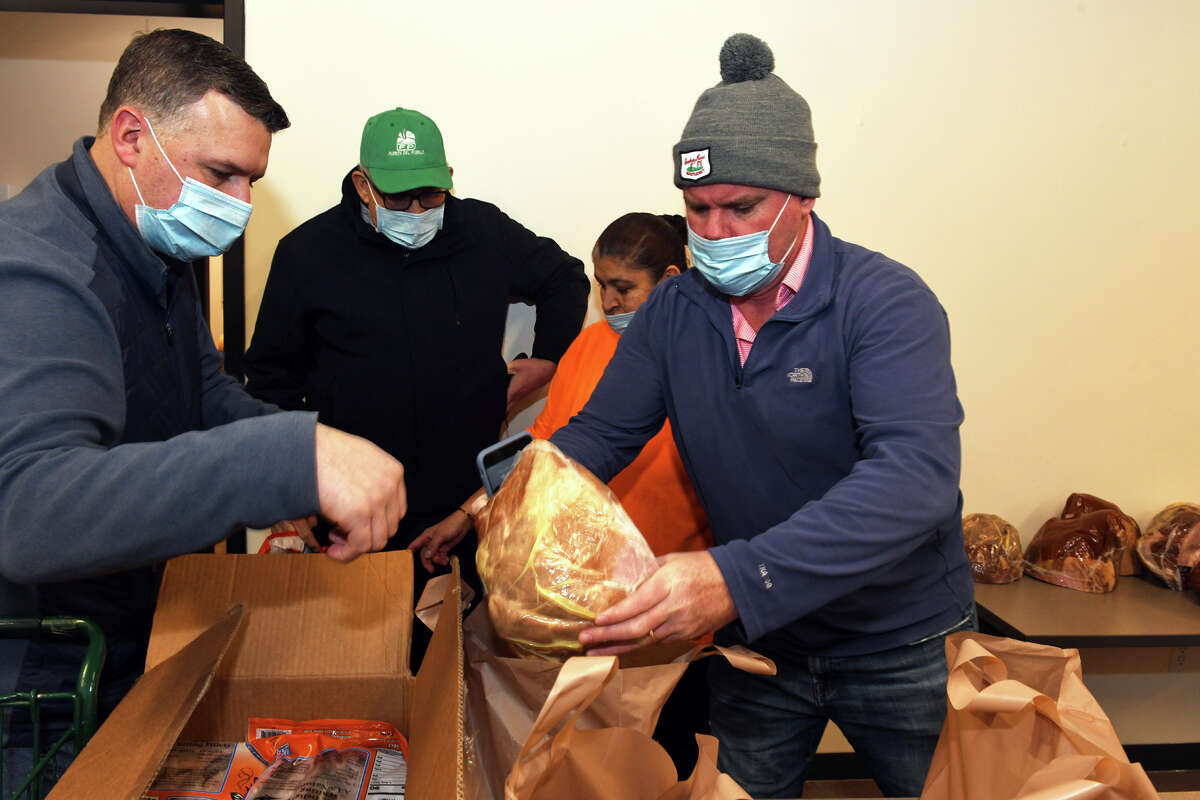 Dave Spezzano, left, and Brad Westbrook, right, volunteers from First Congregational Church, in Darien, help prepare holiday dinner baskets at the Open Doors Smilow Life Center, in Norwalk, Conn. Dec. 22, 2022.