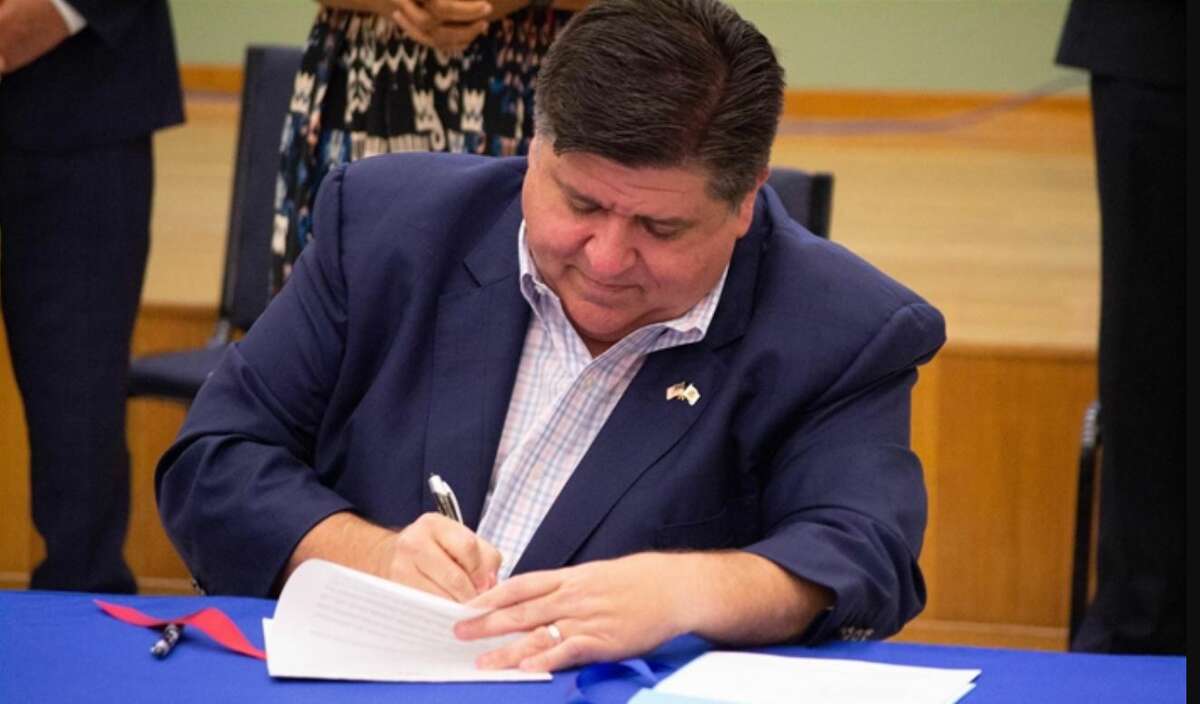 Gov. J.B. Prtizker is shown signing one of the many new laws that will go into effect in 2023.