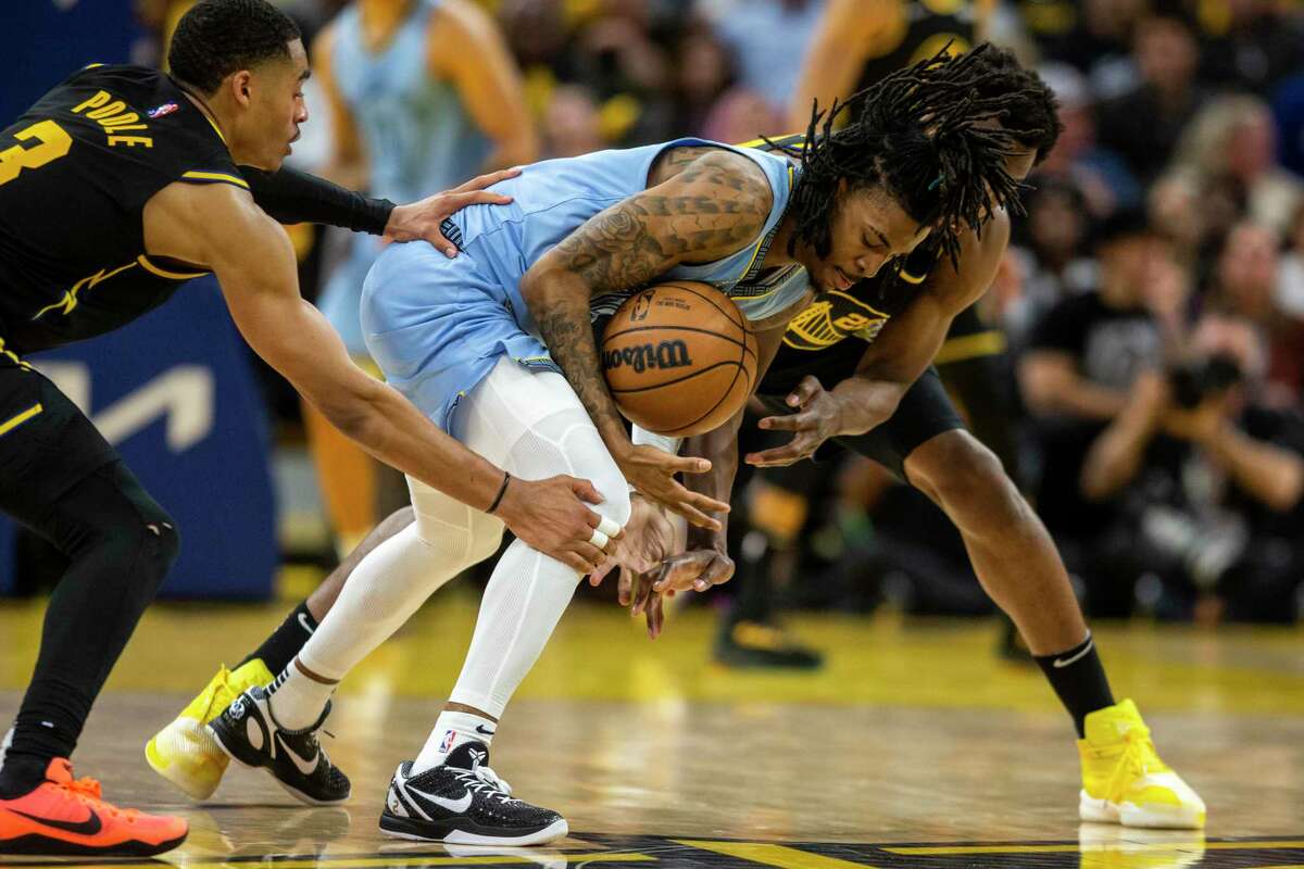 Memphis Grizzlies' guard Ja Morant dribbles the ball as he is defended by Golden State Warriors’ guard Jordan Poole, left, and forward Andrew Wiggins during the fourth quarter in Game 3 of the 2022 NBA Playoffs Western Conference Semifinals at Chase Center in San Francisco, Calif. Saturday, May 7, 2022. The Warriors defeated the Grizzlies 142-112.