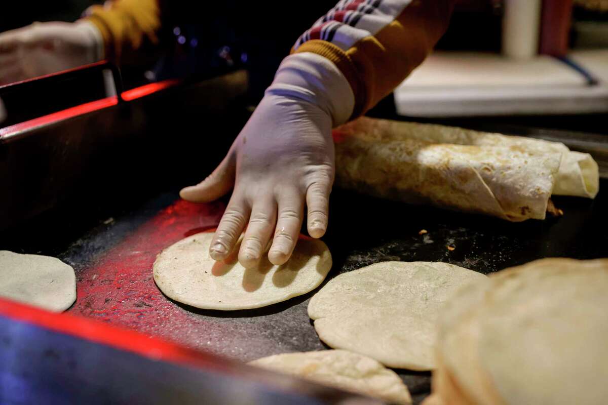 in Oakland, Calif. on Wednesday, Dec. 21, 2022. Cynthia Solorsano cooks hand-made tortillas at a food stand known as Shucos Magi, owned and operated by Maria Rodas, known as Magi, and her family in Fruitvale in Oakland, Calif. on Wednesday, Dec. 21, 2022.