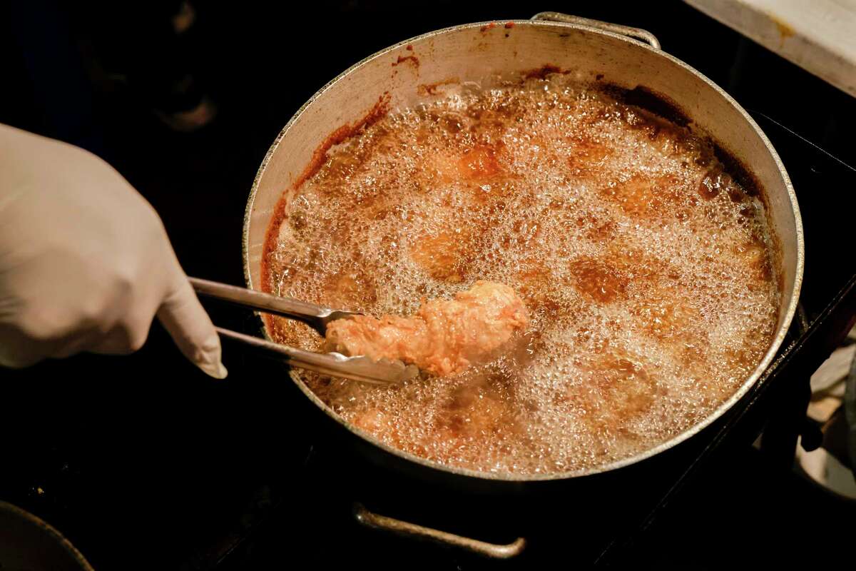 Edwin Mancilla fries chicken while serving Guatemalan food with his family a part of the food stand Shucos Magi in Fruitvale in Oakland, Calif. on Wednesday, Dec. 21, 2022.