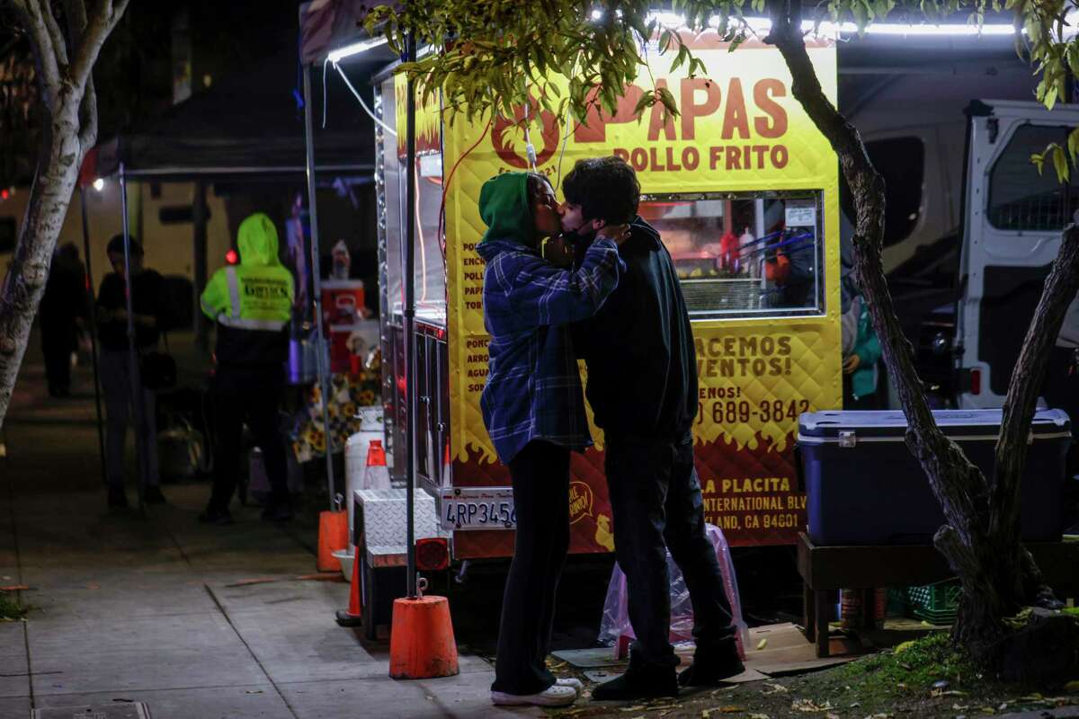 15岁的卡拉尼·罗伯斯(左)在弗鲁特维尔的一个小吃摊上等炸鸡和薯条时亲吻了16岁的吉奥·扎平。由于大量危地马拉移民的涌入，这一地区很容易就能买到经典的危地马拉美食——玉米饼(Papas con pollo)。
