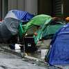 2022年12月1日星期四，在加利福尼亚州旧金山的默特尔街，一排帐篷上覆盖着各种防水布和雨伞。周二晚上，旧金山的气温降至35度以下，促使市政府官员开设了许多取暖中心。