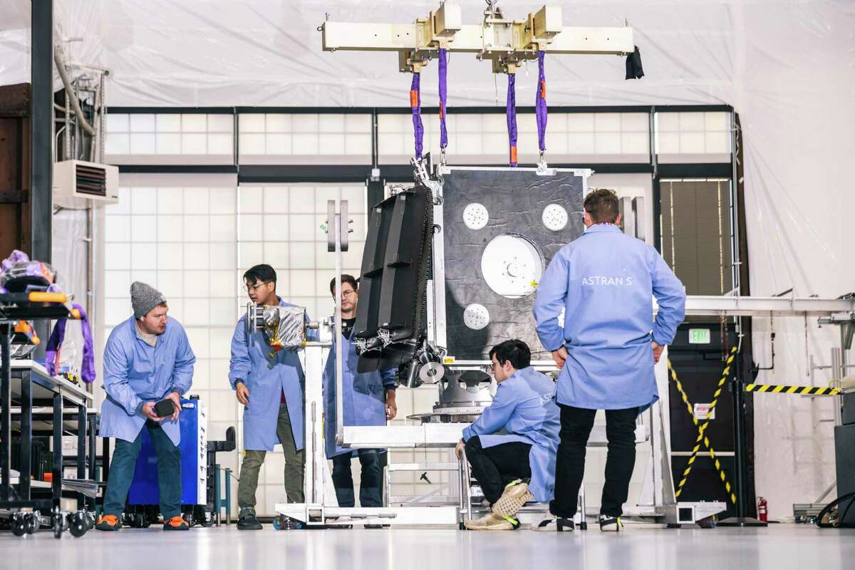 Technicians work on a full-size satellite mockup at Astranis headquarters at San Francisco’s historic Pier 70.