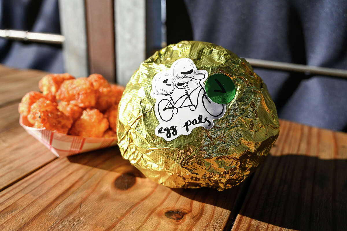 A veggie sandy made with two fried eggs, roasted delicata squash, American cheese, pickled red onion, herby mayo and a brioche bun wrapped in foil.