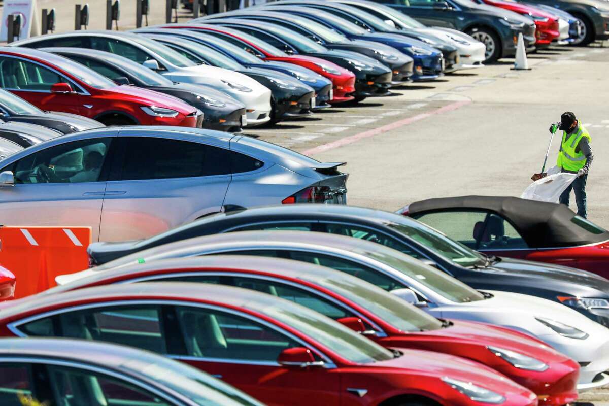 A man cleans the parking lot at the Tesla car factory in 2020 in Fremont, Calif.