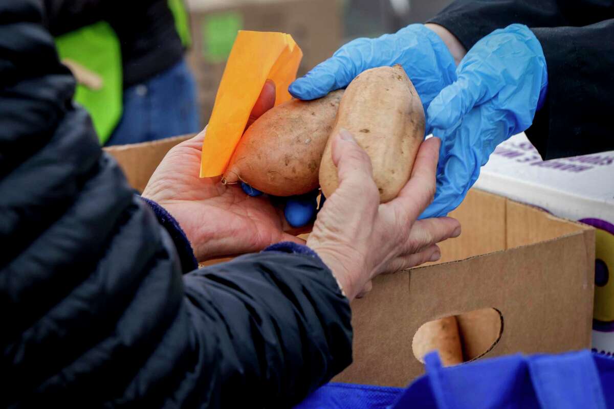Volunteers hand out produce to people at the San Mateo Event Center in San Mateo, Calif., Thursday.
