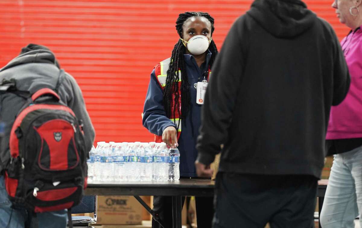 An worker  with the Houston Health Dept., passes retired  h2o  to radical   utilizing the exigency  warming halfway  astatine  George R. Brown Convention Center connected  Thursday, Dec. 22, 2022 successful  Houston. The metropolis  plans to support  the warming center, which has chairs, nary  cots, unfastened  until Saturday.