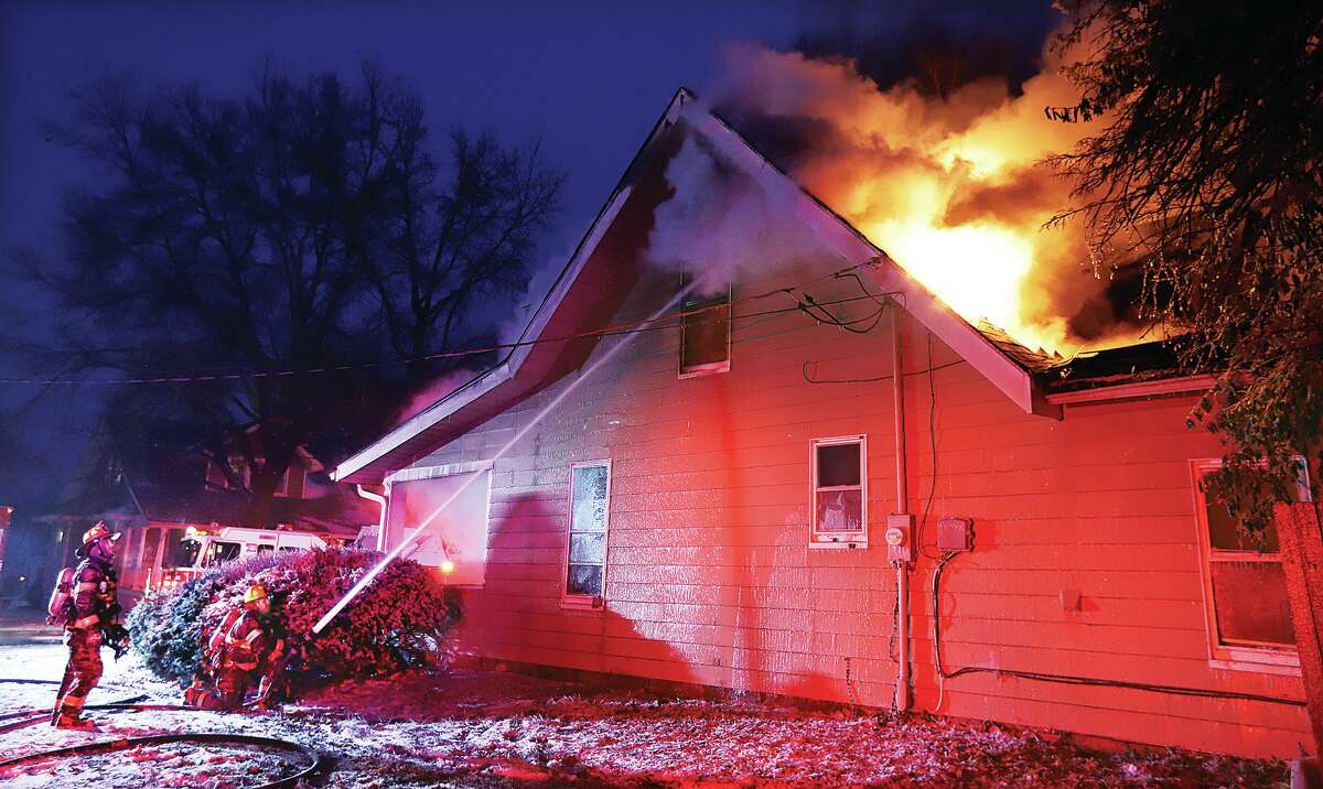 John Badman|The Telegraph Battling flames and temperatures hovering at 1 degree, Alton firefighters pour water on a house on fire Thursday evening in the 1800 block of Main Street. Off-duty firefightes, and firefighters from East Alton and Godfrey, were called to the scene to assist during the hours-long fire.