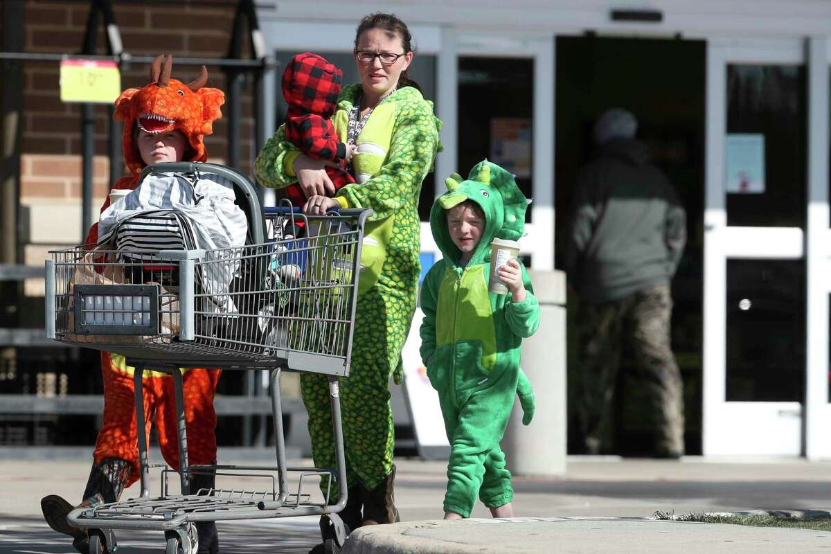 Konnor Knox, left, and his brother, Killian, dress up in dinosaur costumes alongside their mother, Ashley, and baby brother, Corbin, after securing toppings for the family’s hot chocolate bar after an arctic freeze swept through the region, Friday, Dec. 23, 2022, in Montgomery. 