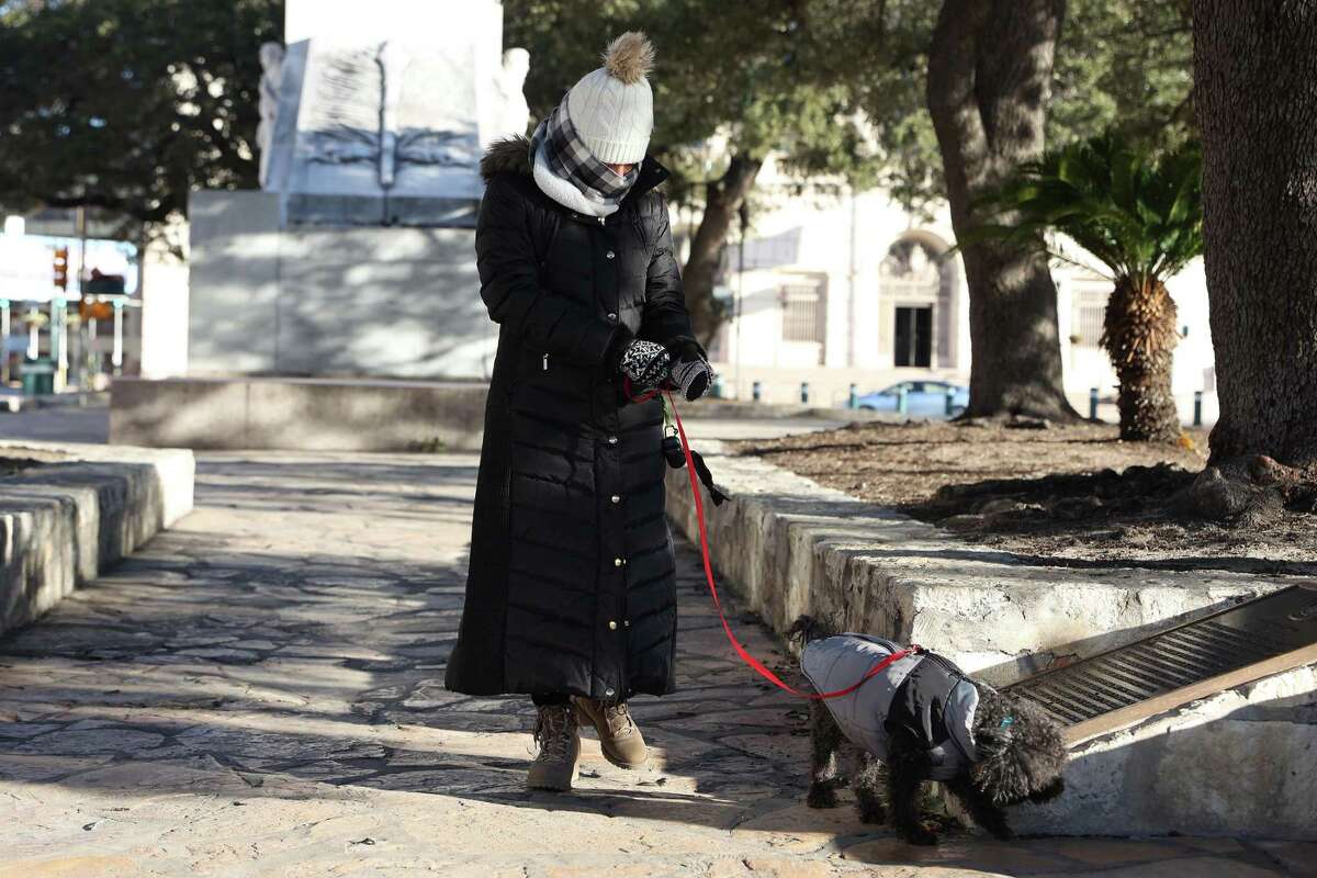 Diana Morales, of Stephenville, Texas, walks her dog, Lucas, at Alamo Plaza, Friday, Dec. 23, 2022. A strong cold front brought wind chill factors in the single digits. Thousands are without power in Bandera County.
