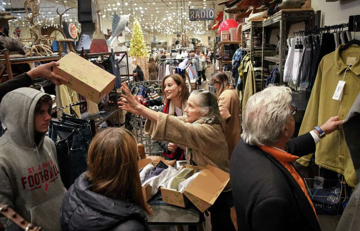 Pam Kuhl-Linscomb, co-owner of the Kuhl-Linscomb department store, reaches for a box of shoes from an associate as she helps Hannah Badrei, to her right, shop for shoes for her husband Friday, Dec. 23, 2022, at her store in Houston. Badrei, a former Houstonian, is visiting from Seattle. “I love this place, so unique,” she said.