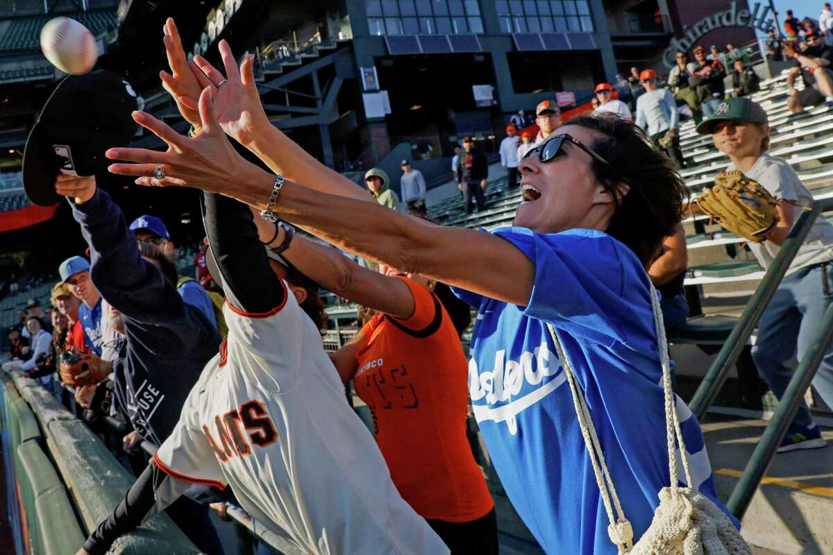 Trina Carter dives for the baseball thrown into the bleachers by the Los Angeles Dodgers outfield during batting practice ahead of an MLB game against the San Francisco Giants at Oracle Park in San Francisco, Calif., Friday, Sept. 16, 2022. Carter travelled to the park from Gardnerville, Nevada, for the game.