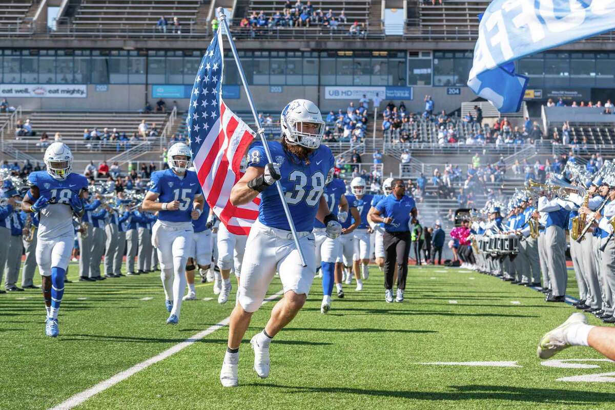 University at Buffalo defensive end Damian Jackson, a 30-year-old former Navy SEAL, carries the U.S. flag as the team takes the field before a game against Toledo in Buffalo, N.Y.