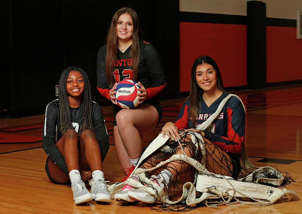 Volleyball players Cornerstone’s Nayeli Gonzalez, draped with net, Clark’s Kaitlin Whitlock and New Braunfels’s Canyon Megan Hawkins, holding the ball, pose on Dec. 7 at TMI-Episcopal gym. The three are the Express-News finalists for Player of the Year.