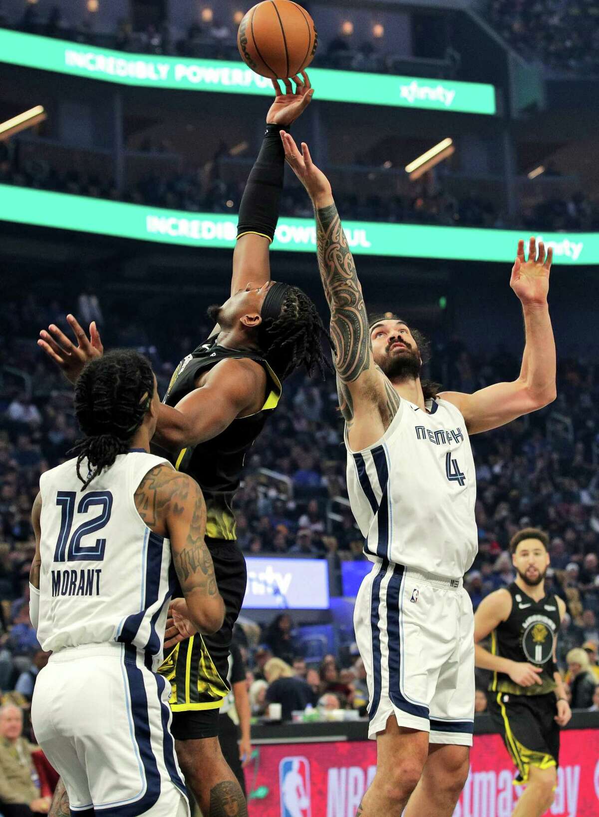 Kevon Looney (5) reaches a rebound ahead of Stephen Adams (4) In the first half as the Golden State Warriors played the Memphis Grizzlies at Chase Center in San Francisco, Calif., on Sunday, December 25, 2022.