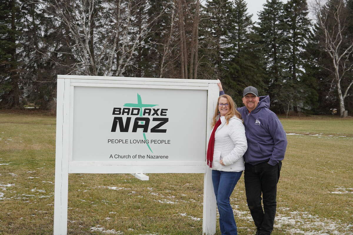 Missy and Rich Evans in front of their sign to the Bad Axe Naz where their motto "People Loving People" is present for people to see.