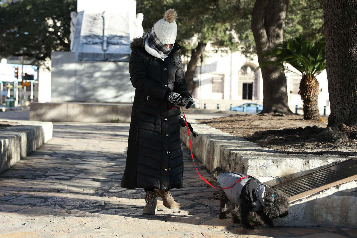 Diana Morales, of Stephenville, Texas, walks her dog, Lucas, at Alamo Plaza on Friday, Dec. 23, 2022. A strong cold front brought wind chill temperatures into the single digits. 