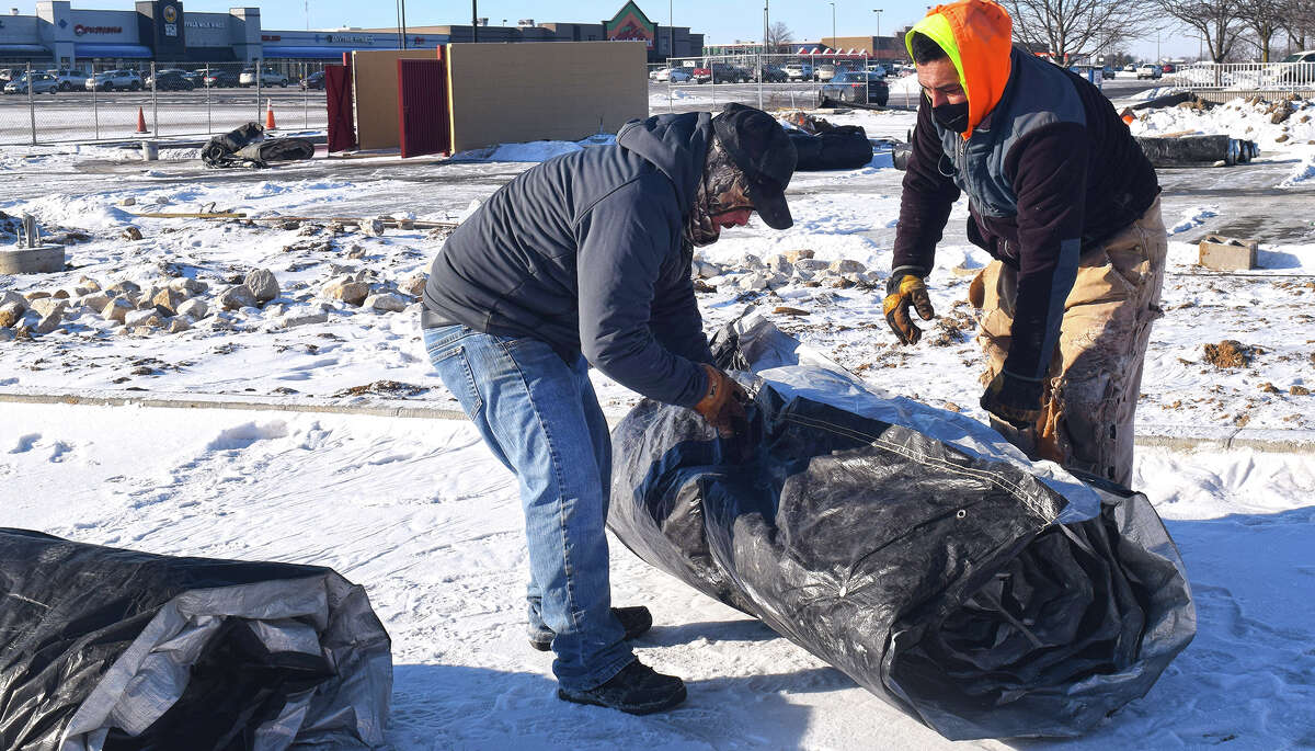 Sergio Vasquez (left) and Martin Santos of Jaren Industries spend a cold morning rolling and wrapping tarps in the 1200 block of West Morton Avenue. They were preparing the site of what will become a 7 Brew coffee shop and a Take 5 oil change shop. Temperatures that had been in the single-digits or below during the weekend rose Tuesday into the high 20s and are expected to reach almost 60 degrees by Thursday.