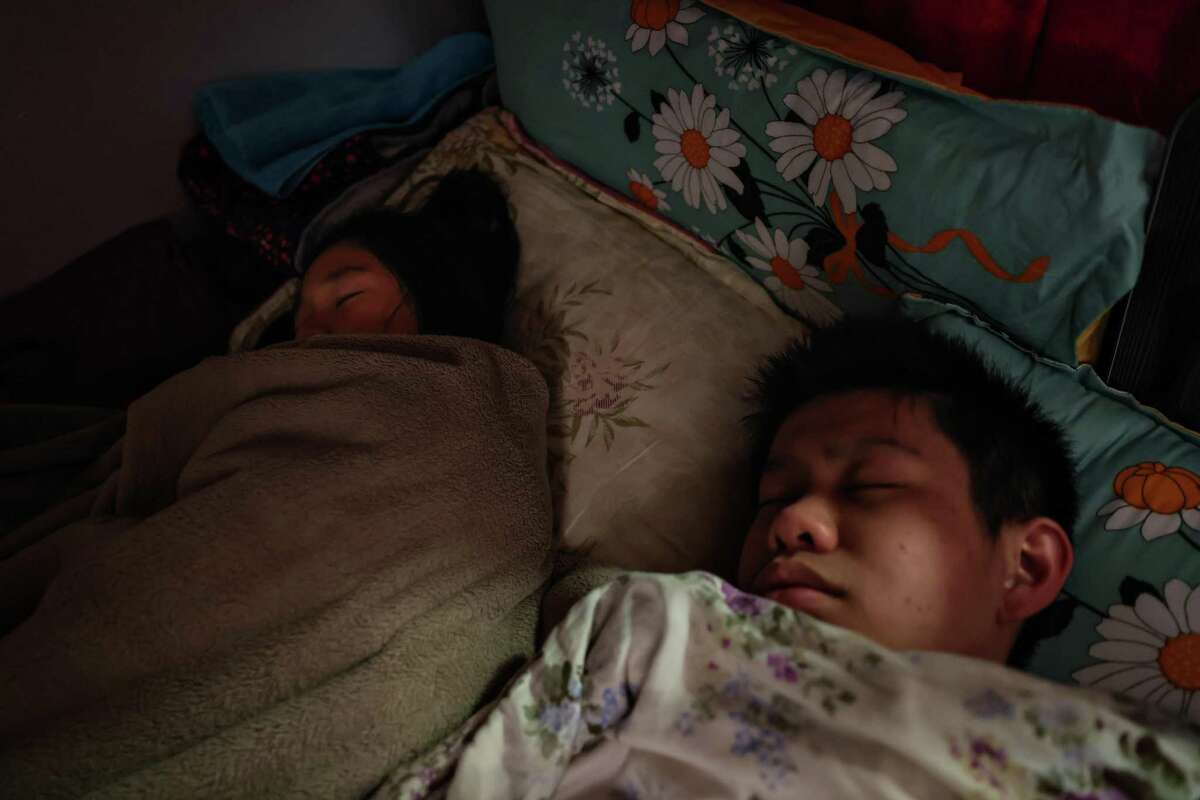 Winnie Tan, 8, and her brother William Tan, 16, sleep in the early morning at their SRO in Chinatown in San Francisco, California on Sunday, April 24, 2022. A main reason the Tan’s moved is because they wanted Winnie to have her own bed.